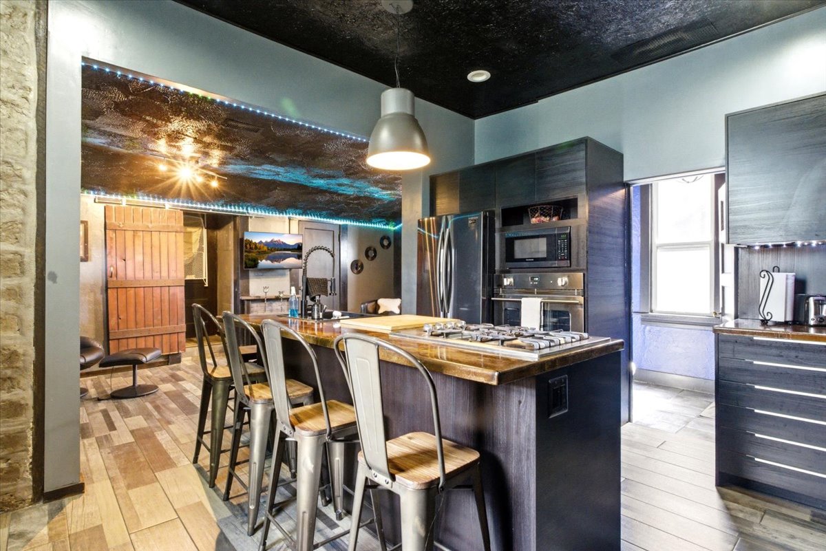 Kitchen featuring dark cabinetry, stainless steel appliances, and a central island with an integrated cooktop
