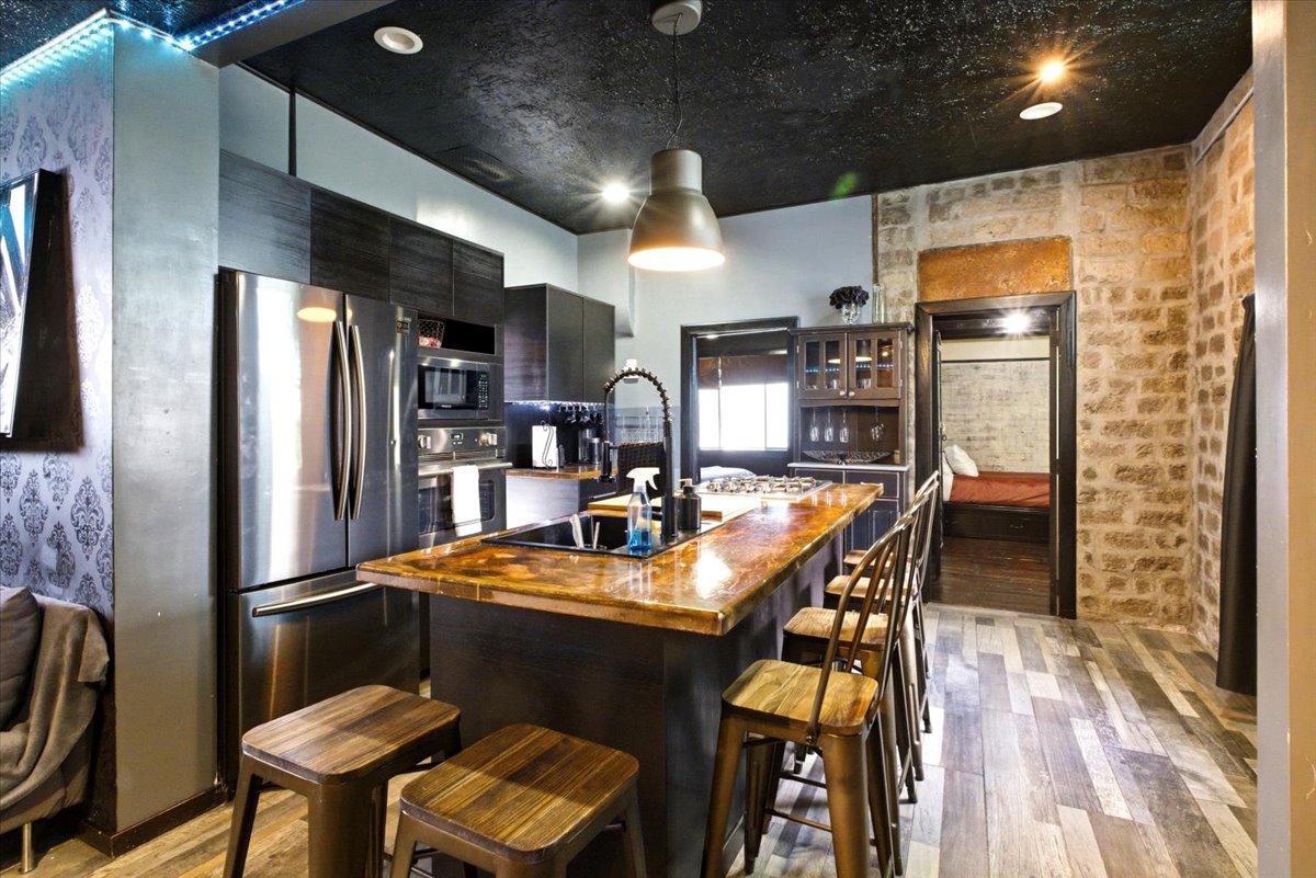 Modern kitchen featuring stainless steel appliances, dark wood-finish cabinetry, and a central island with a wood-finish countertop