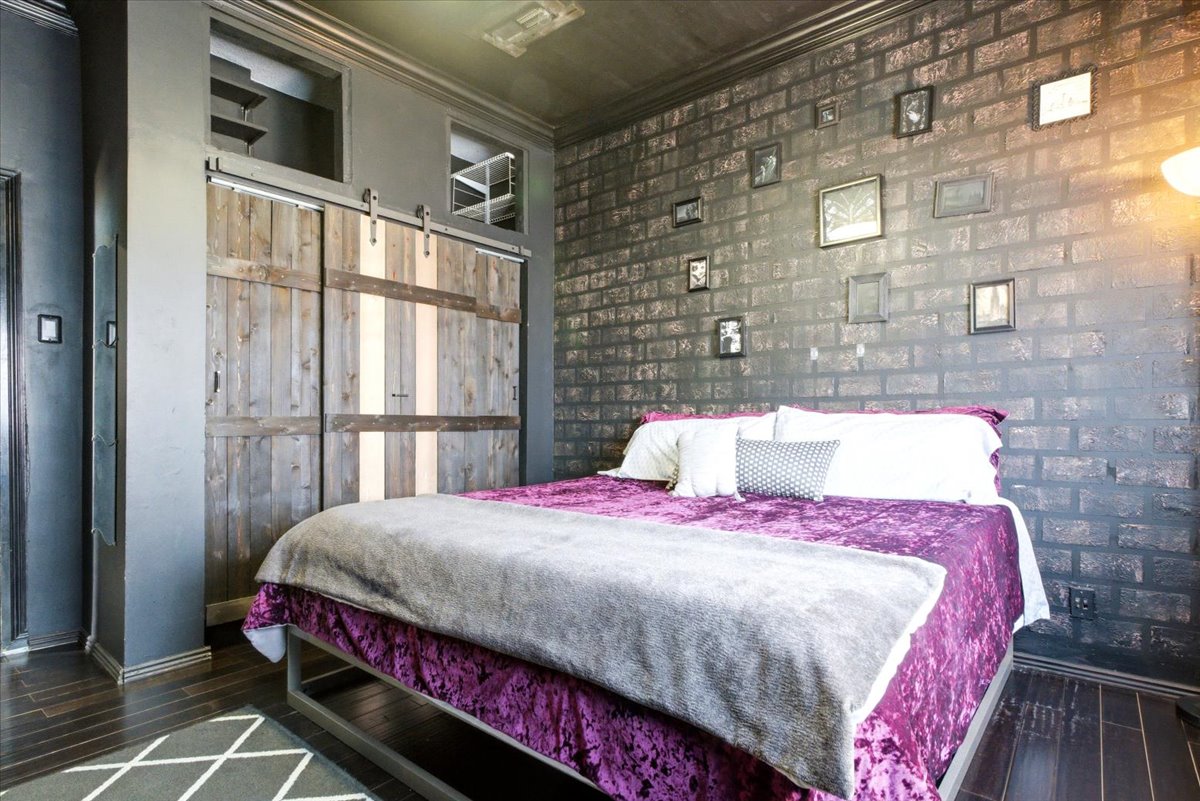 Interior featuring dark wood-finish flooring, a full-height brick accent wall, and a built-in storage unit with sliding barn doors