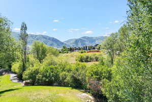 Expansive outdoor grounds featuring a rolling lawn and mature trees, surrounded by distant mountains