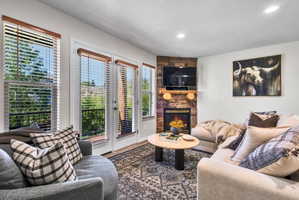 Corner fireplace featuring a stone surround and a rustic wood mantel
