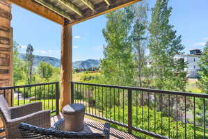Balcony featuring a wood-finish deck, robust log column, and a stone-clad wall