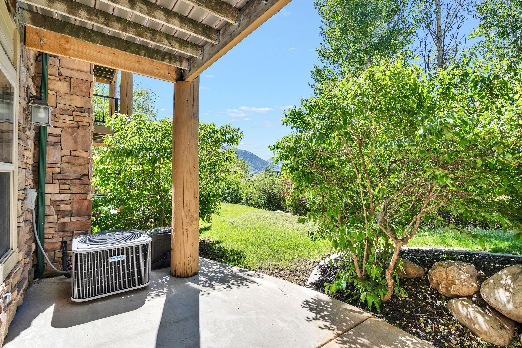 Covered patio featuring a stacked stone exterior and wooden support beams