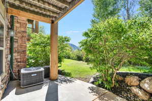 Covered patio featuring a stacked stone exterior and wooden support beams