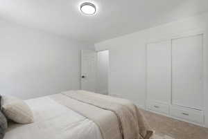 Spacious room featuring neutral carpeting, a modern flush-mount ceiling light, and a built-in closet with sliding doors and integrated lower drawers