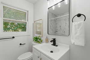 Bathroom featuring a white vanity with integrated sink, black hardware, framed mirror, and window