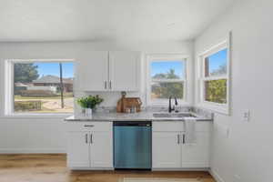 Kitchenette featuring white shaker cabinetry, speckled countertop, stainless steel sink with a matte black faucet, and a panel-ready dishwasher