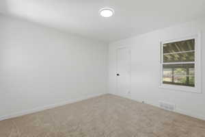Carpeted room featuring a white paneled door with matte black hardware, a double-hung window, and a ceiling-mounted flush light fixture