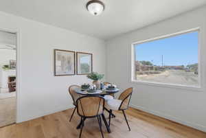 Dining area featuring wood-finish flooring, white baseboards, a large picture window, and a ceiling-mounted light fixture
