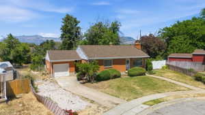Brick exterior ranch home with an attached garage, a paved driveway, and established front landscaping