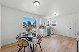 Kitchen area featuring wood-finish flooring, white cabinetry with dark hardware, light countertops, and a built-in dishwasher