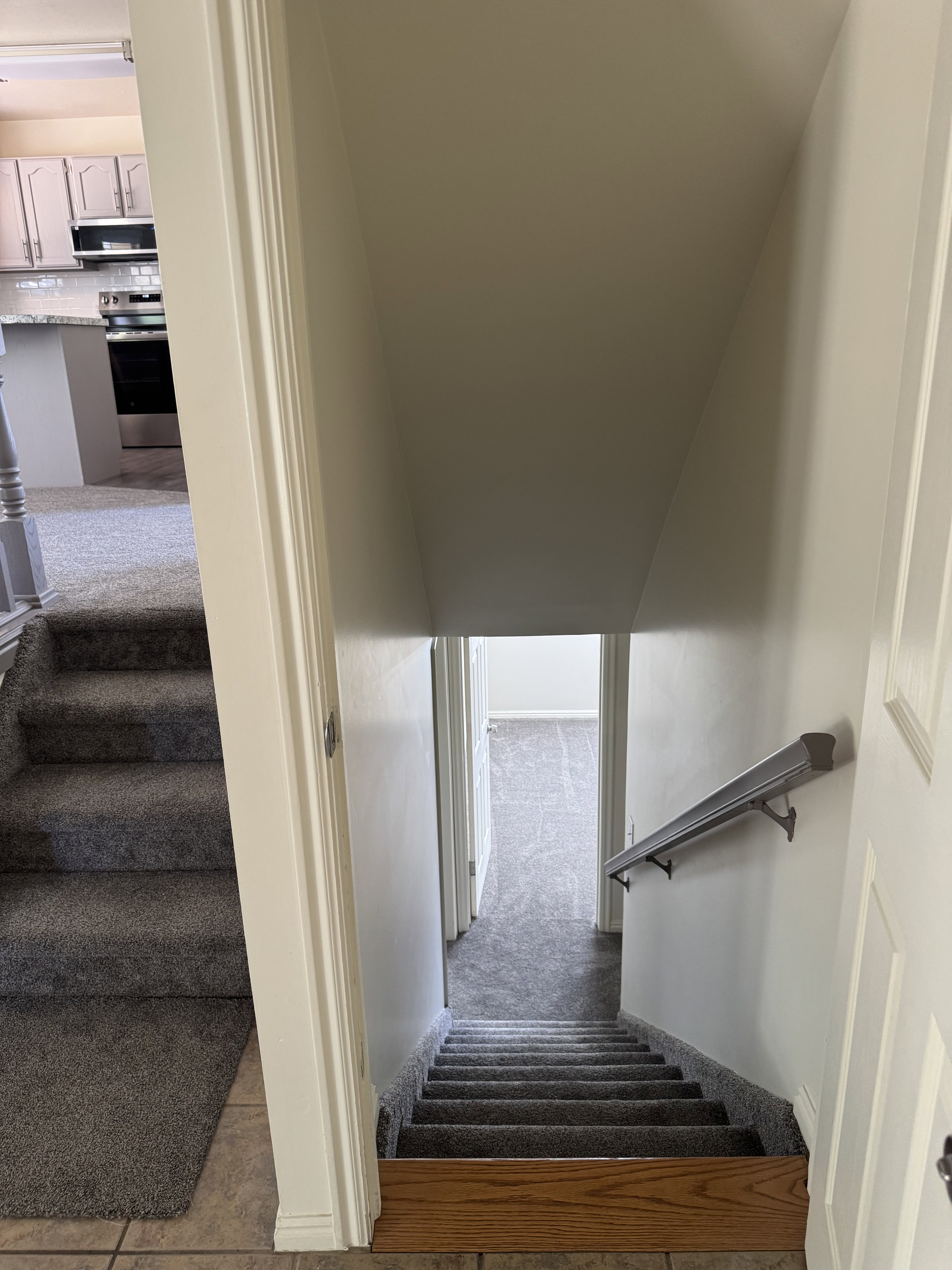 Carpeted staircase with a wood-finish landing and a light-toned handrail