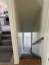 Carpeted staircase with a wood-finish landing and a light-toned handrail
