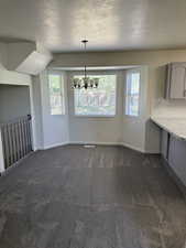 Dining area featuring a bay window, chandelier lighting, and gray carpet flooring