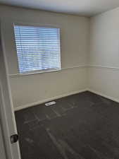 Carpeted room with a window featuring horizontal blinds
