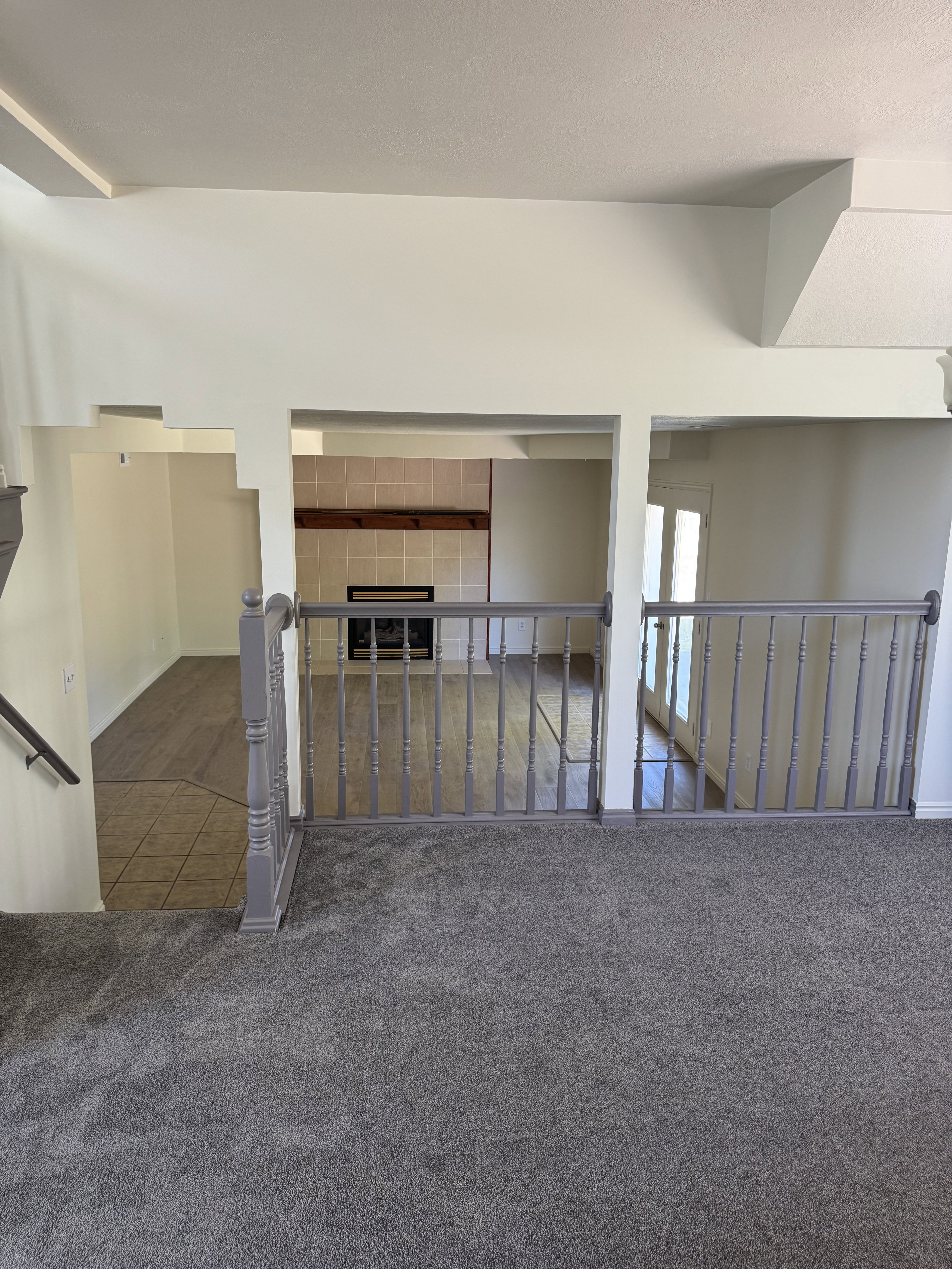Multi-level interior featuring a gray carpeted upper level and wood-finish flooring below