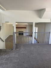 Multi-level interior featuring a gray carpeted upper level and wood-finish flooring below