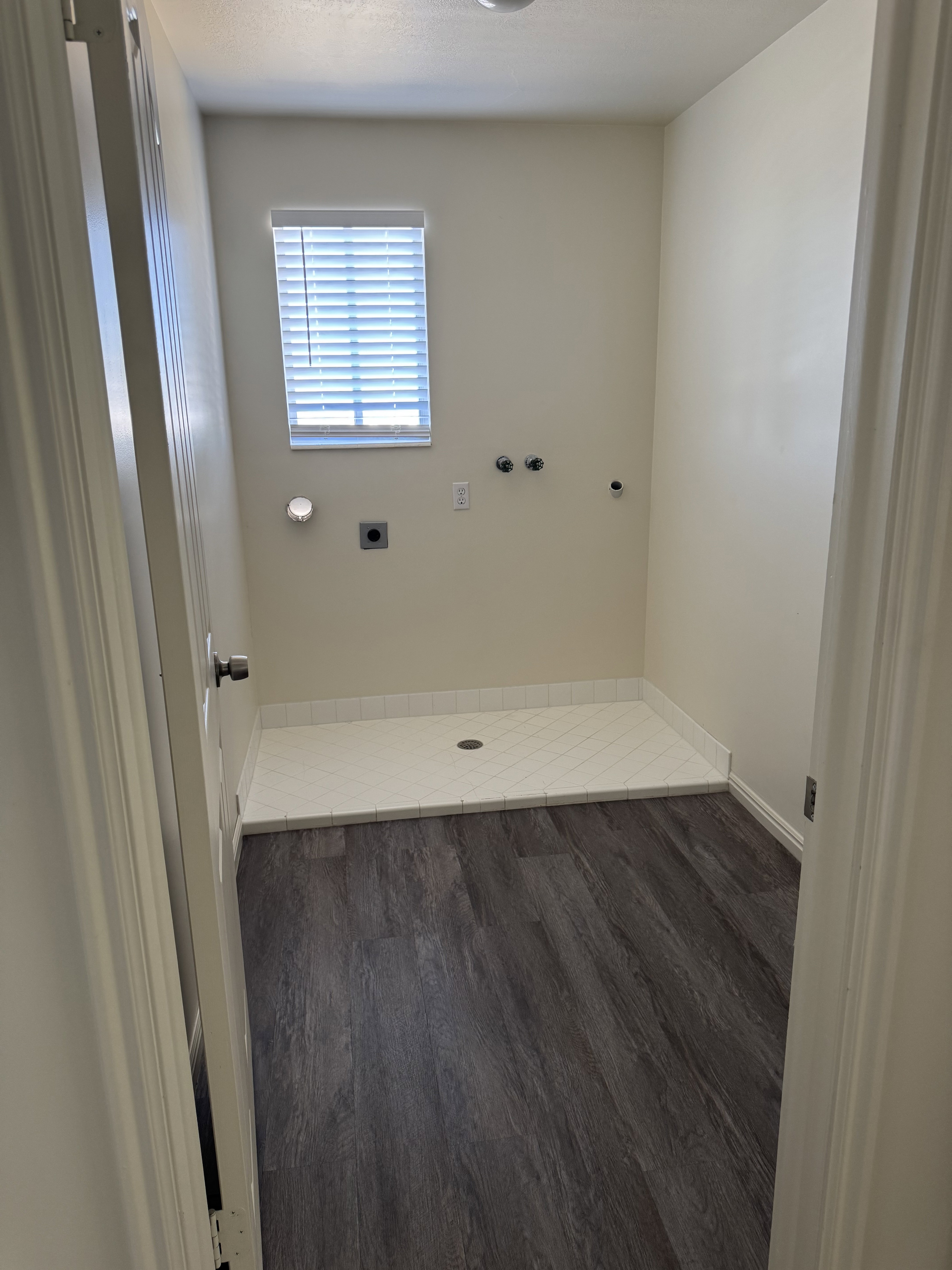 Laundry area featuring wood-finish flooring and a tiled utility pan