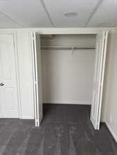 Integrated closet featuring bi-fold panel doors, white interior walls, and a hanging rod
