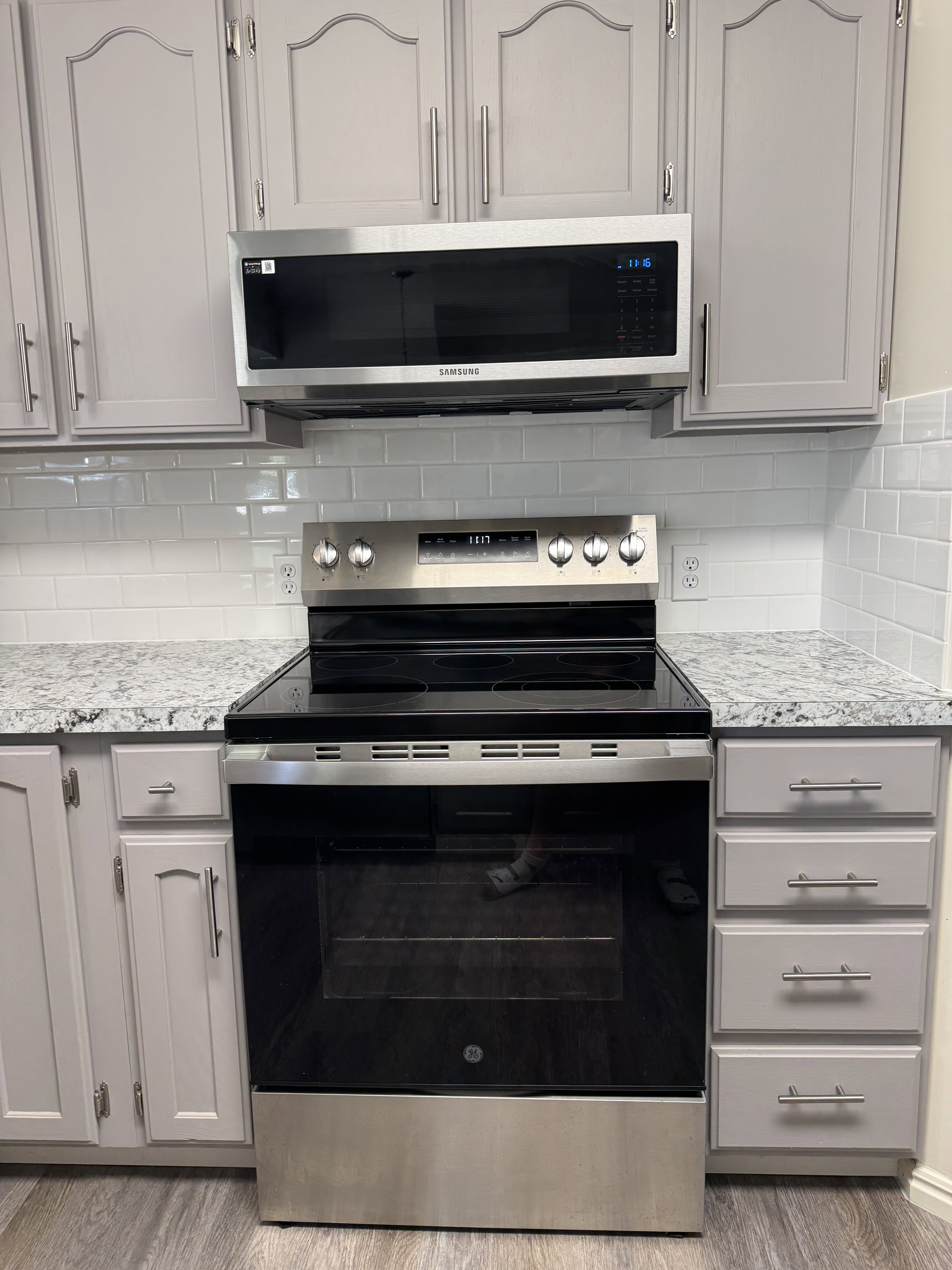 Kitchen featuring stainless steel appliances, light gray cabinetry, and a white subway tile backsplash