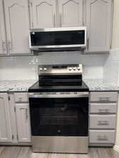 Kitchen featuring stainless steel appliances, light gray cabinetry, and a white subway tile backsplash