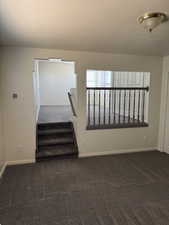 Multi-level interior featuring a carpeted staircase with white risers and a dark gray handrail