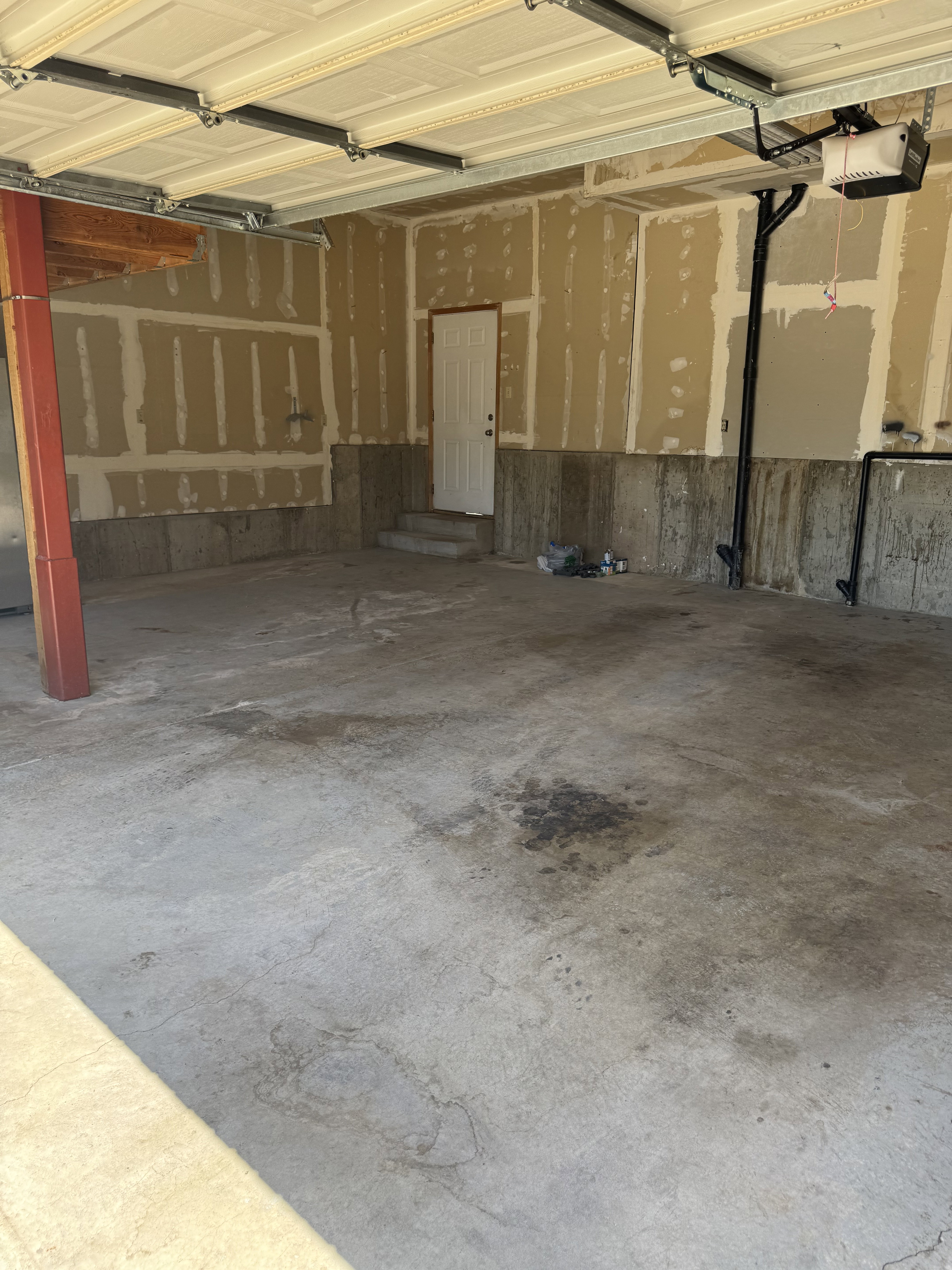 Attached garage space featuring a concrete floor, overhead door mechanism, and a side entry door