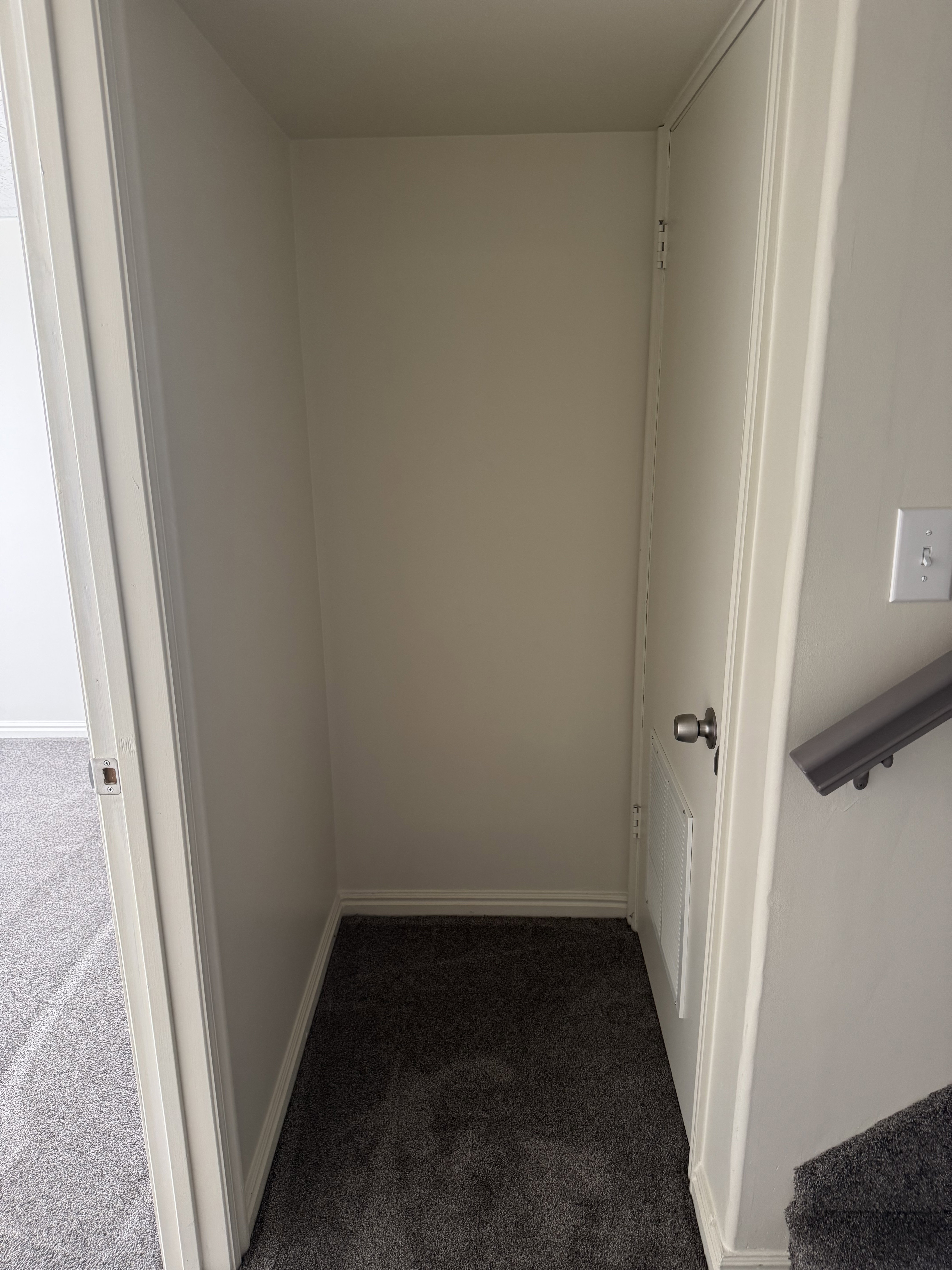 Recessed alcove with dark grey carpet flooring, white baseboards, and light neutral walls