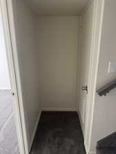 Recessed alcove with dark grey carpet flooring, white baseboards, and light neutral walls