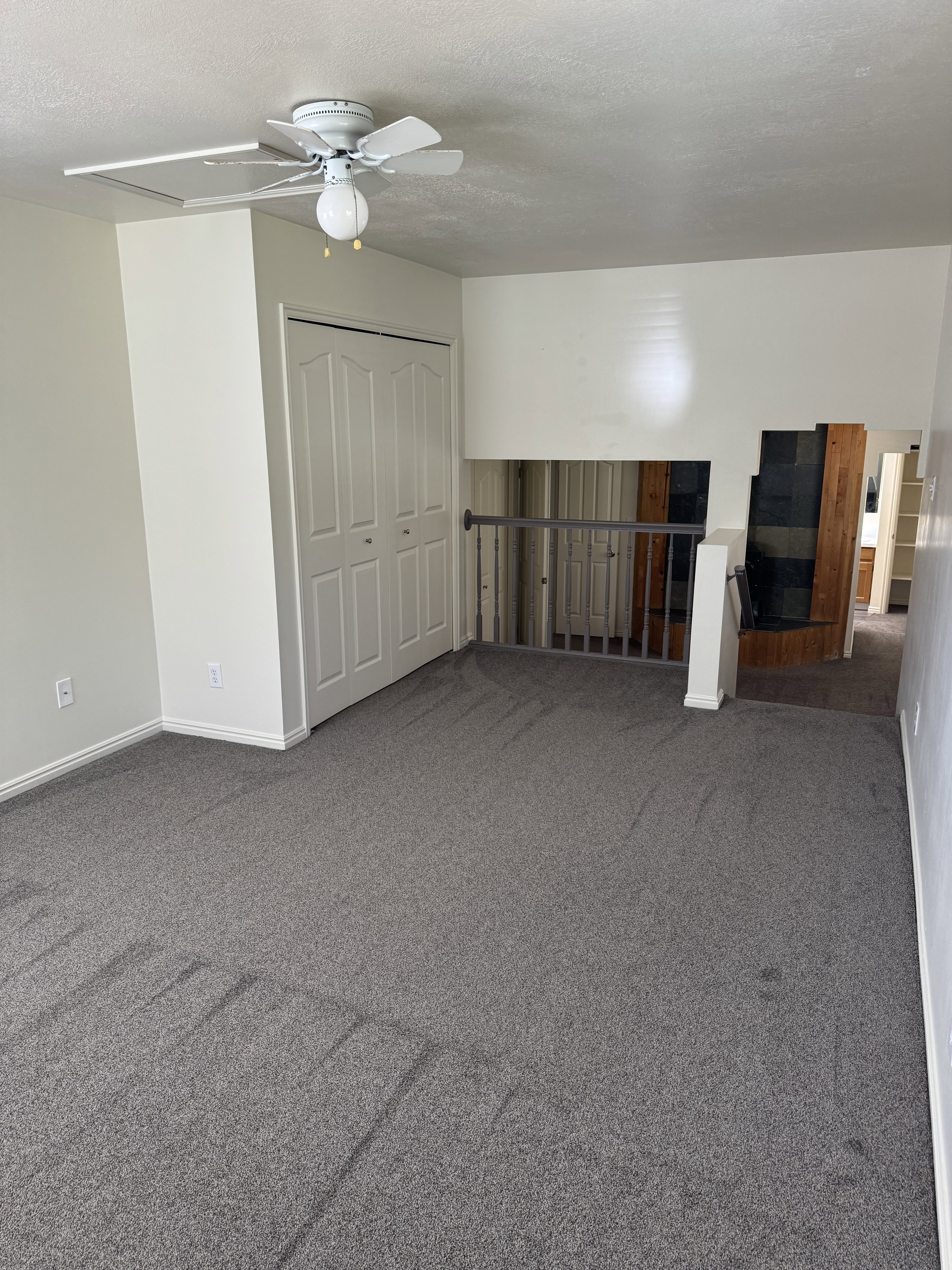 Carpeted room featuring a ceiling fan with light, bi-fold closet doors, and painted baseboards