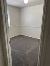 Room featuring light neutral wall colors, chair rail molding, wall-to-wall gray carpeting, a single window with horizontal blinds, and a ceiling-mounted light fixture