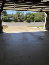 Garage interior with a concrete floor and an open overhead door, offering access to the exterior drive and street