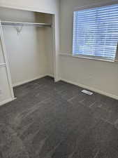 Interior room featuring plush gray carpeting, white walls, and a window with blinds