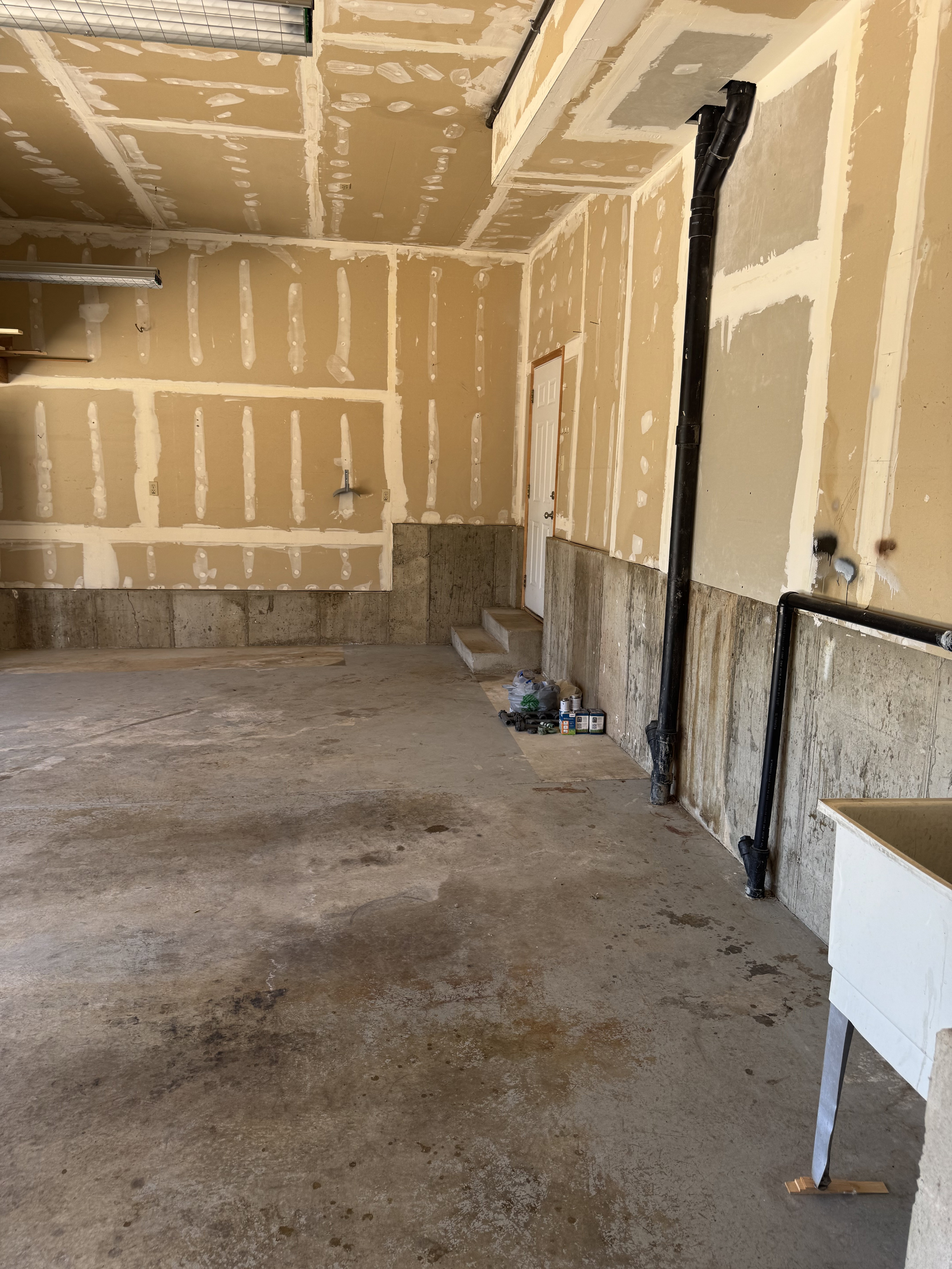 Unfinished garage interior with concrete flooring and exposed drywall