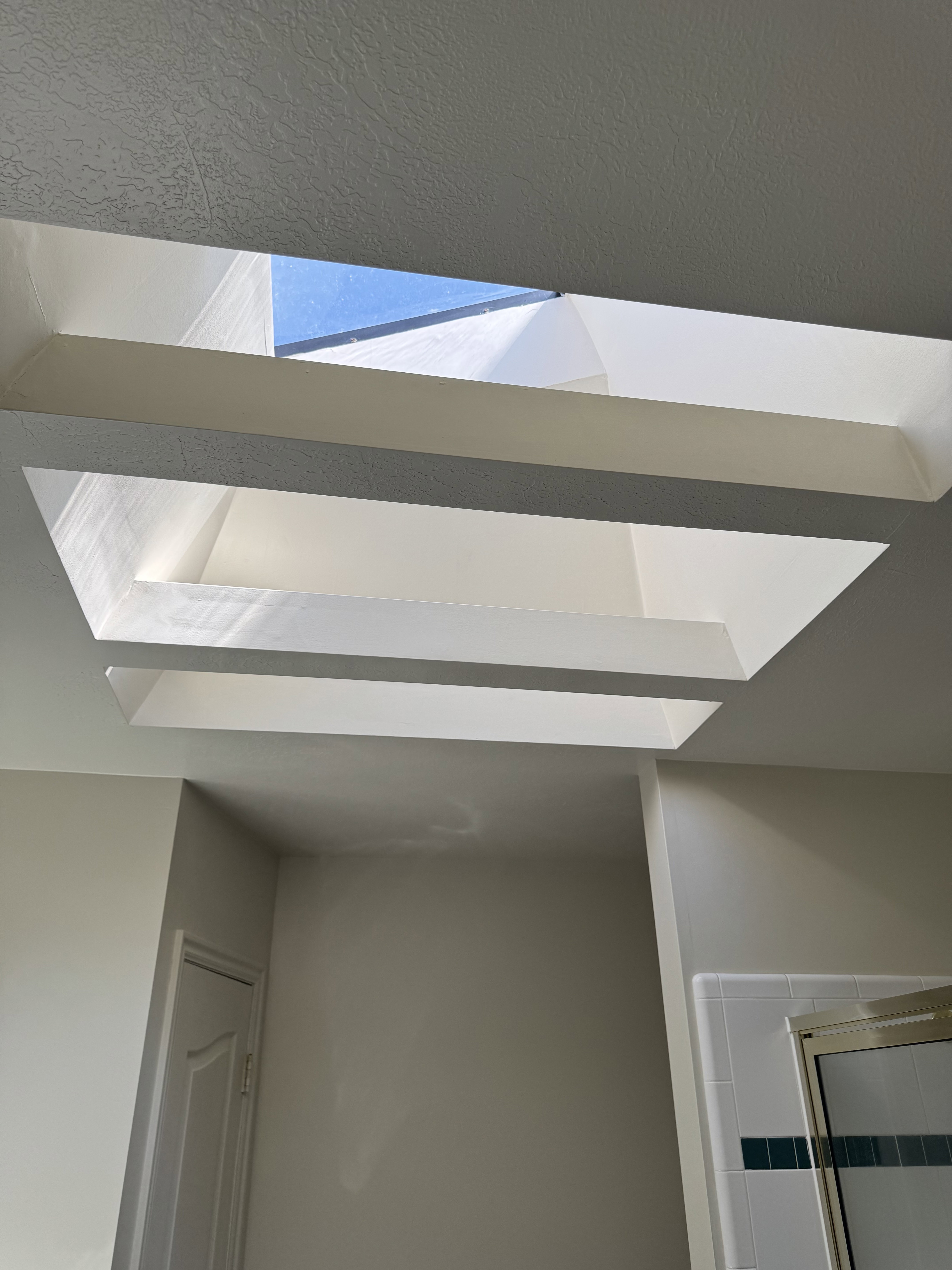 Recessed skylight feature with a rectangular opening and tiered light well, providing natural illumination