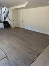 Spacious interior featuring wood-finish flooring, a carpeted staircase with a dark wrought iron railing, and neutral wall tones