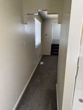 Interior hallway featuring light-colored walls and dark carpet flooring