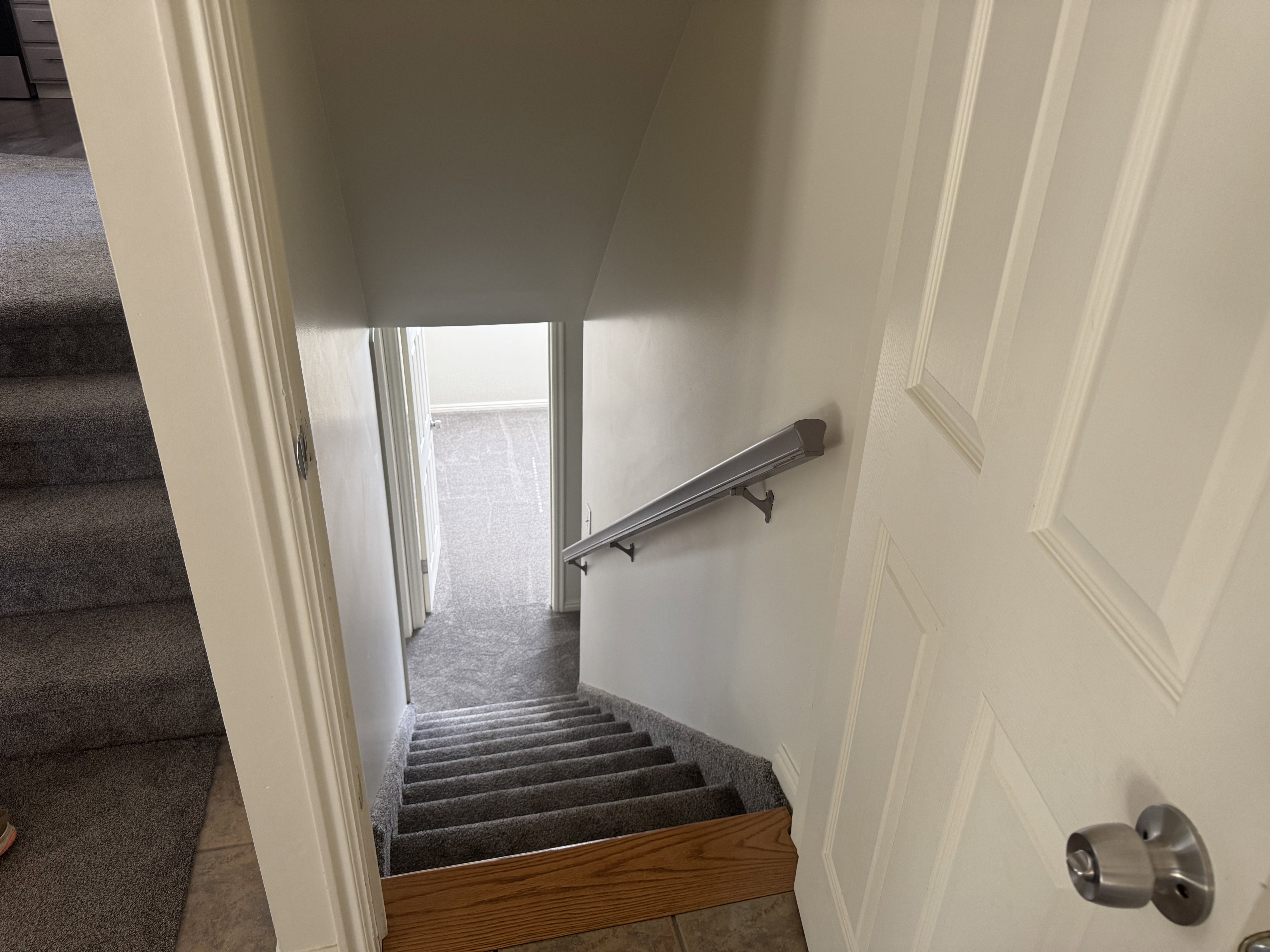 Carpeted staircase with an oak newel post and a metal handrail
