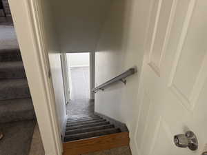 Carpeted staircase with an oak newel post and a metal handrail