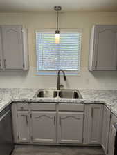 Kitchen featuring light gray cabinetry, a dual basin stainless steel sink, a dark finished faucet, white subway tile backsplash, and light-colored countertops