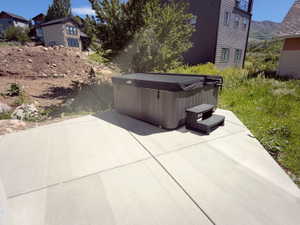 Outdoor patio featuring a hot tub with steps and a cover