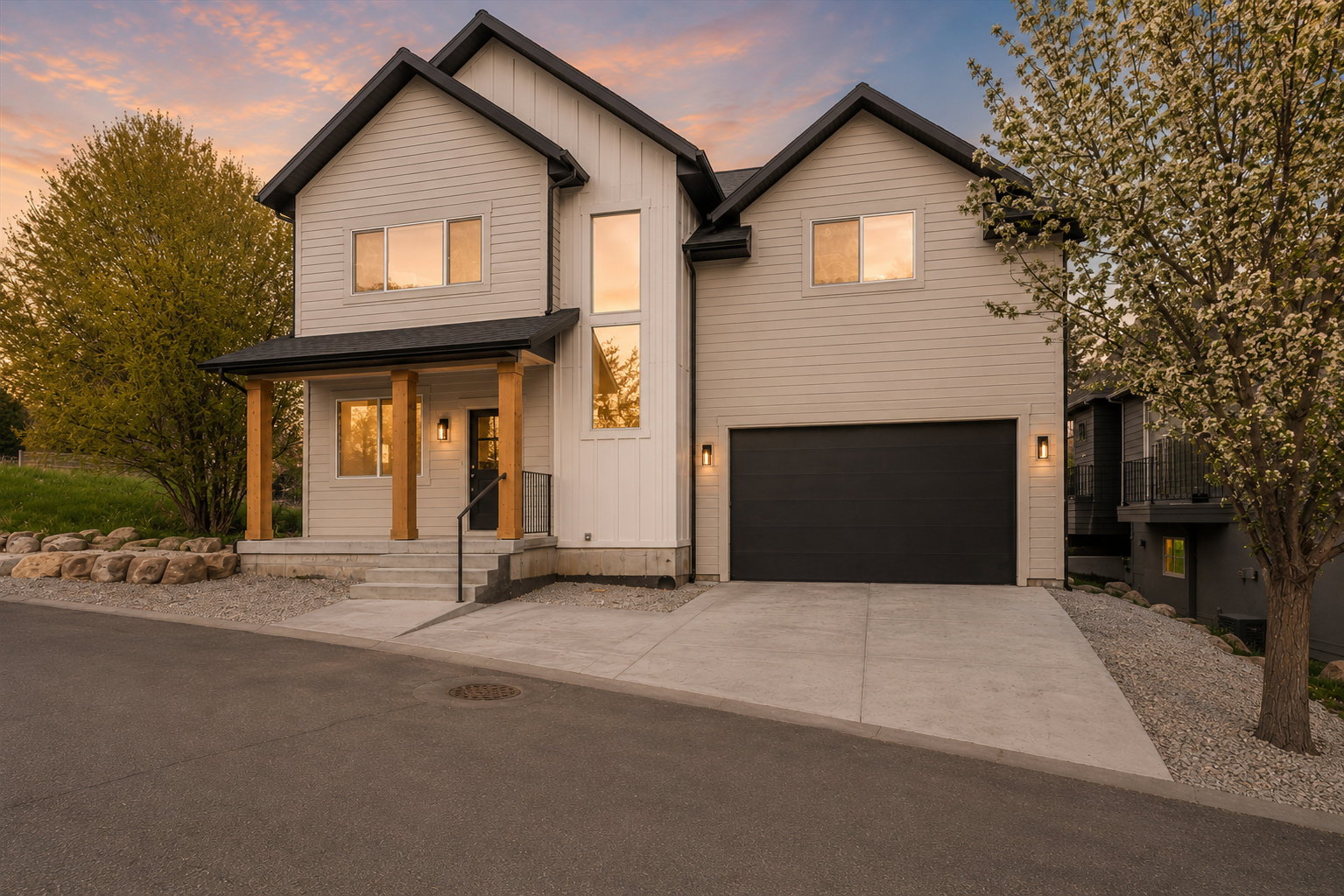 Modern two-story residence featuring a black gabled roofline, light-toned horizontal siding, and vertical board and batten accents