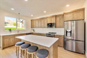 Kitchen featuring wood cabinetry, stainless steel appliances, white subway tile backsplash, white countertops, and wood-finish flooring