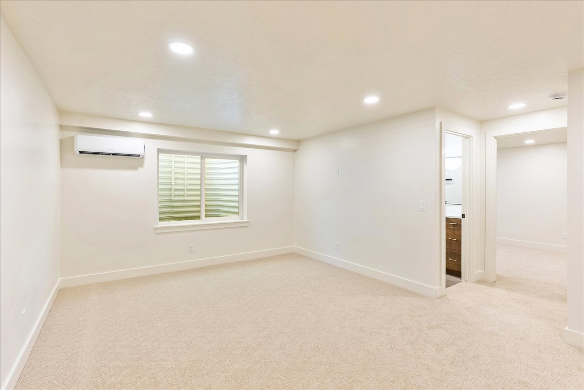 Cream-toned carpeting in a spacious room featuring a window with security grating