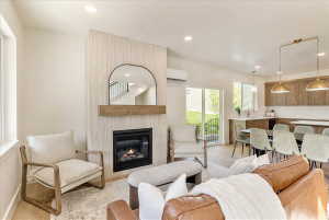 Living space featuring a gas fireplace with a wood mantle and textured surround, recessed lighting, and wood-finish flooring