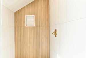 Shower enclosure featuring a wood-panel accent wall and light-toned tile