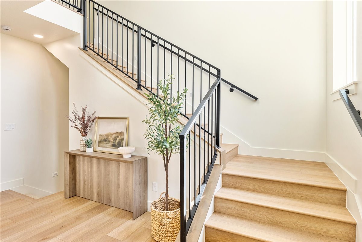 Hardwood staircase featuring black metal railings and a continuous handrail