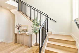 Hardwood staircase featuring black metal railings and a continuous handrail