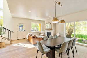 Open-concept living area with abundant natural light, wood-finish flooring, and a contemporary fireplace featuring a tile surround and wooden mantel