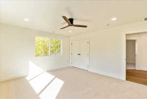 Spacious room featuring carpeted flooring, a ceiling fan with integrated lighting, recessed lighting, and a double-door closet